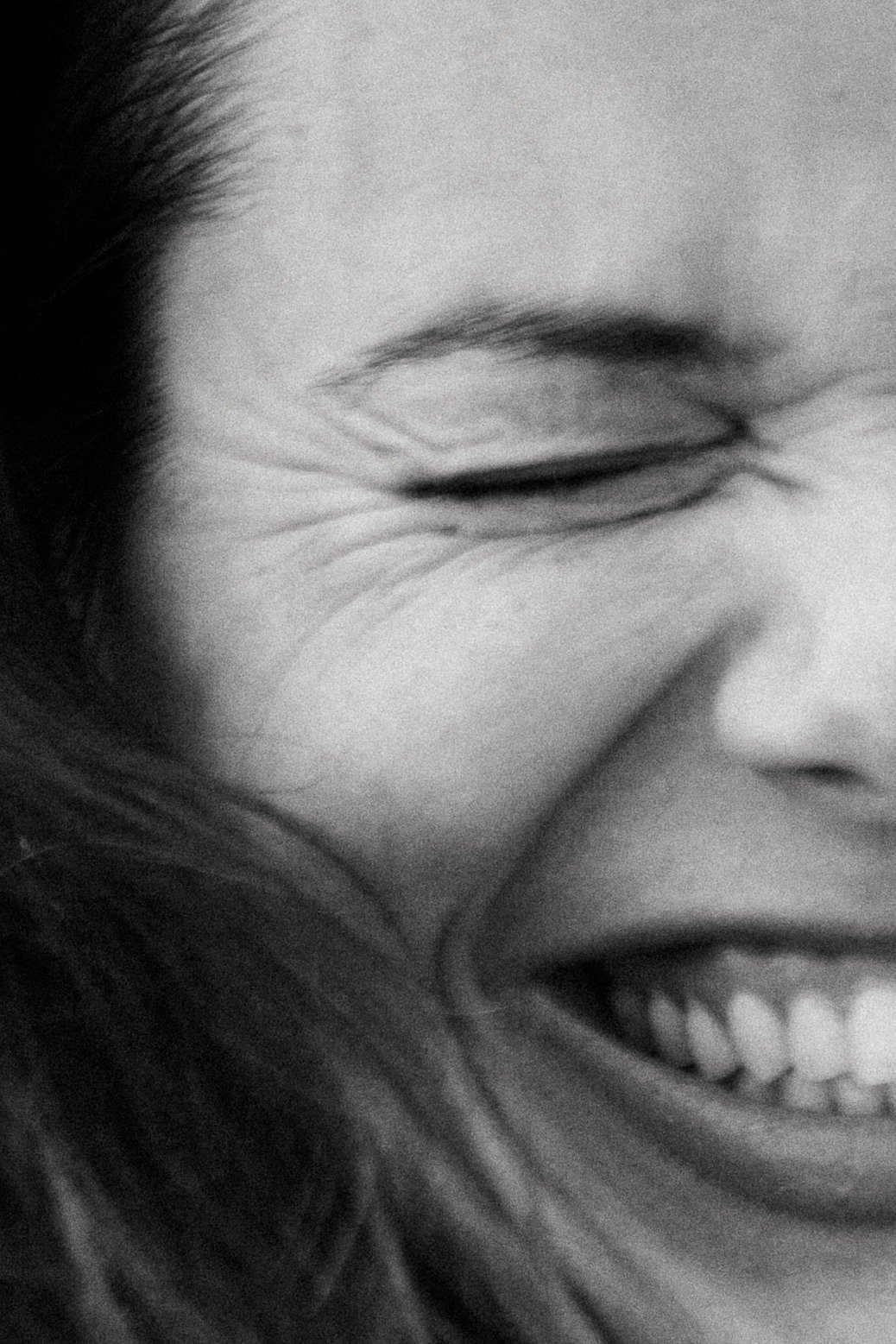Close-up of a smiling face with a closed eye and expression lines